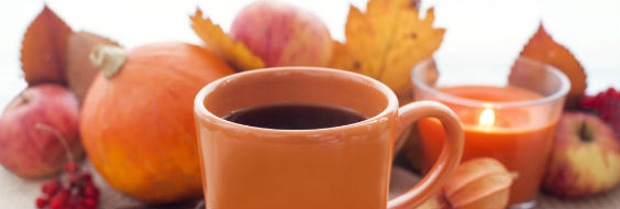 Kaffekop og stearinlys med græsker, æbler og visne blade